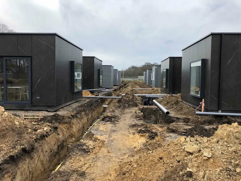 Modulaire woonunits van het nooddorp in Oostakker op schroefpalen, met sleuven voor nutsleidingen